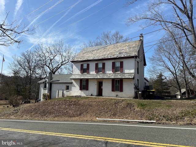 view of front of house featuring a high end roof, a chimney, and stucco siding