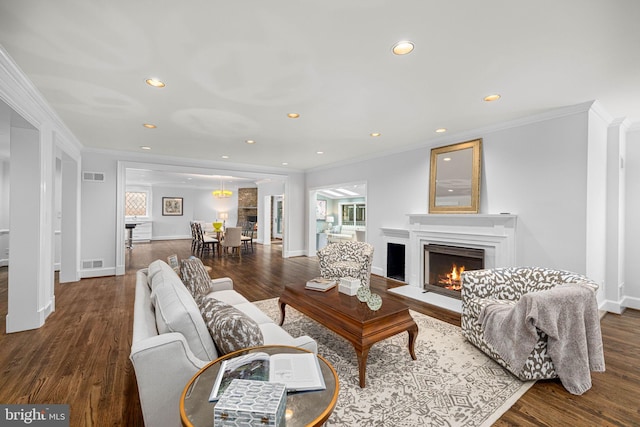 living area with visible vents, crown molding, and wood finished floors