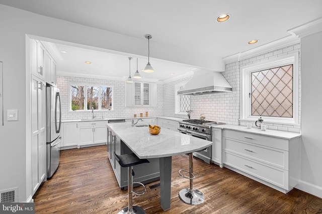 kitchen featuring visible vents, premium range hood, white cabinets, appliances with stainless steel finishes, and a center island