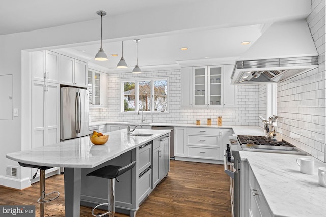 kitchen with dark wood-type flooring, light stone counters, a kitchen breakfast bar, appliances with stainless steel finishes, and custom exhaust hood