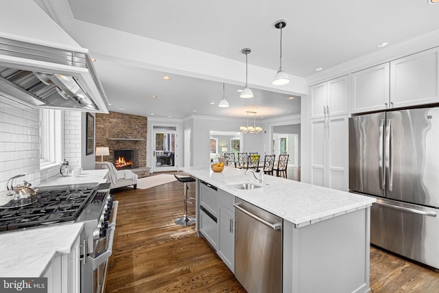 kitchen with a sink, open floor plan, appliances with stainless steel finishes, decorative backsplash, and dark wood-style flooring