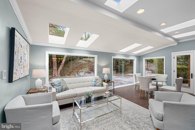 living area featuring recessed lighting, vaulted ceiling with skylight, wood finished floors, and ornamental molding