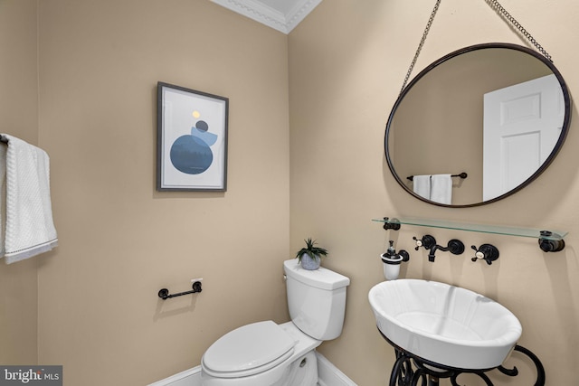 bathroom featuring toilet, crown molding, and baseboards