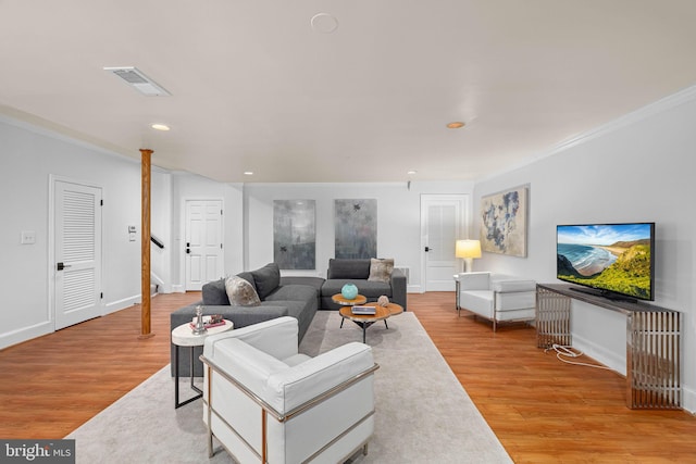 living area with visible vents, ornamental molding, baseboards, and wood finished floors