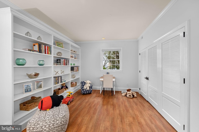 playroom featuring crown molding, light wood-style flooring, built in shelves, and baseboards