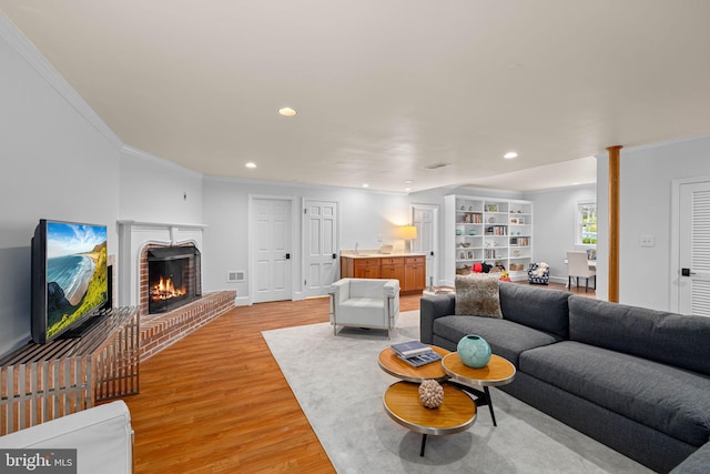 living room featuring crown molding, light wood-style flooring, recessed lighting, and a fireplace