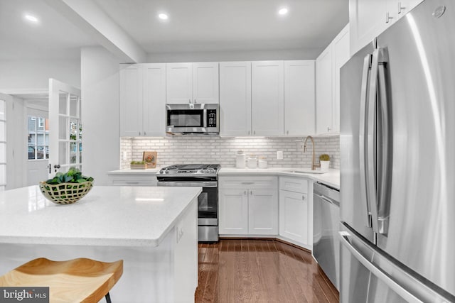 kitchen with a sink, stainless steel appliances, dark wood-style flooring, and white cabinetry