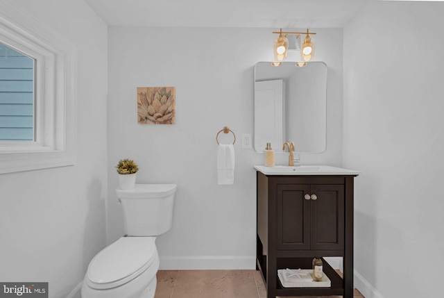 half bath with vanity, toilet, and baseboards