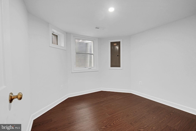 unfurnished room with dark wood-style floors, visible vents, electric panel, and baseboards