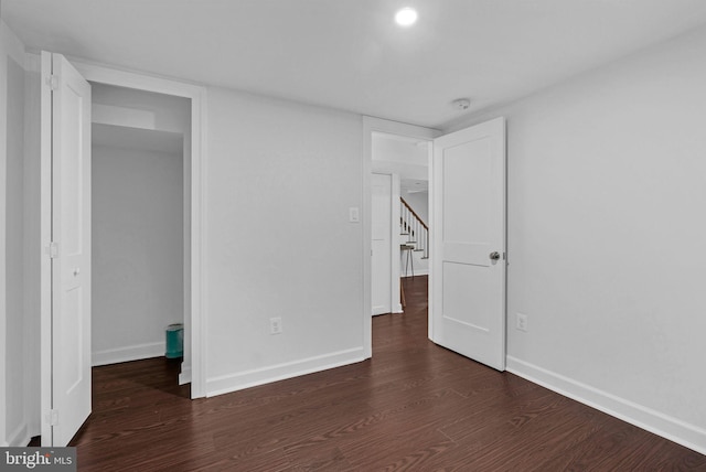 unfurnished bedroom with baseboards and dark wood-style flooring