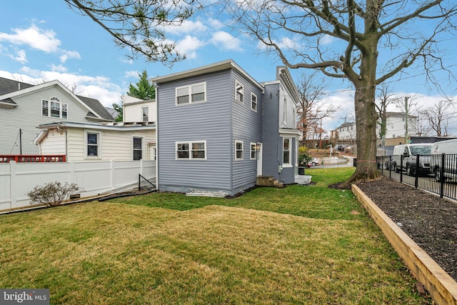 rear view of property featuring a yard and a fenced backyard