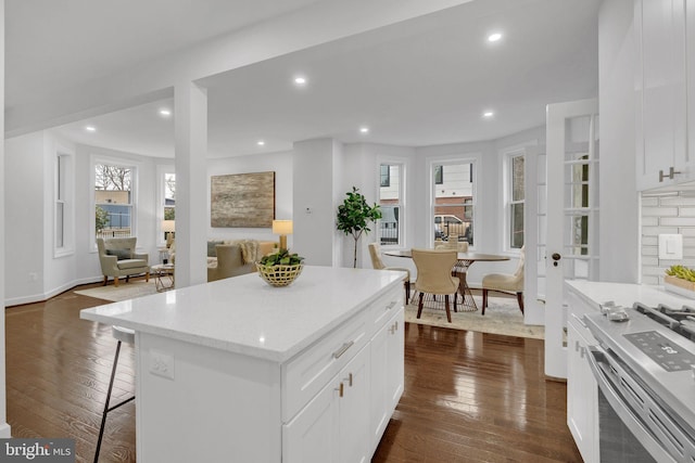 kitchen with dark wood finished floors, gas range, recessed lighting, and a kitchen bar