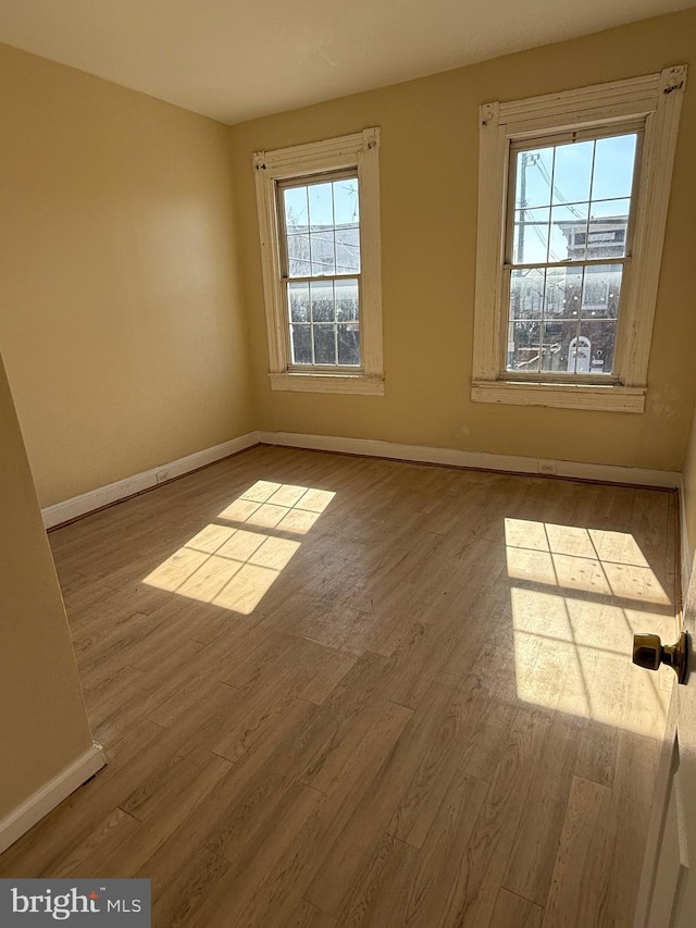 unfurnished room with baseboards and wood finished floors