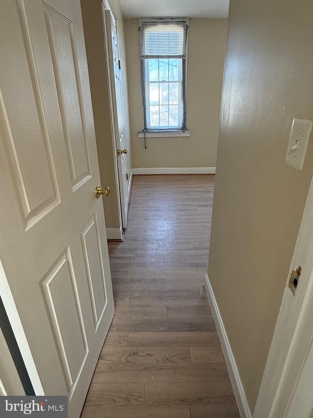 corridor featuring wood finished floors and baseboards