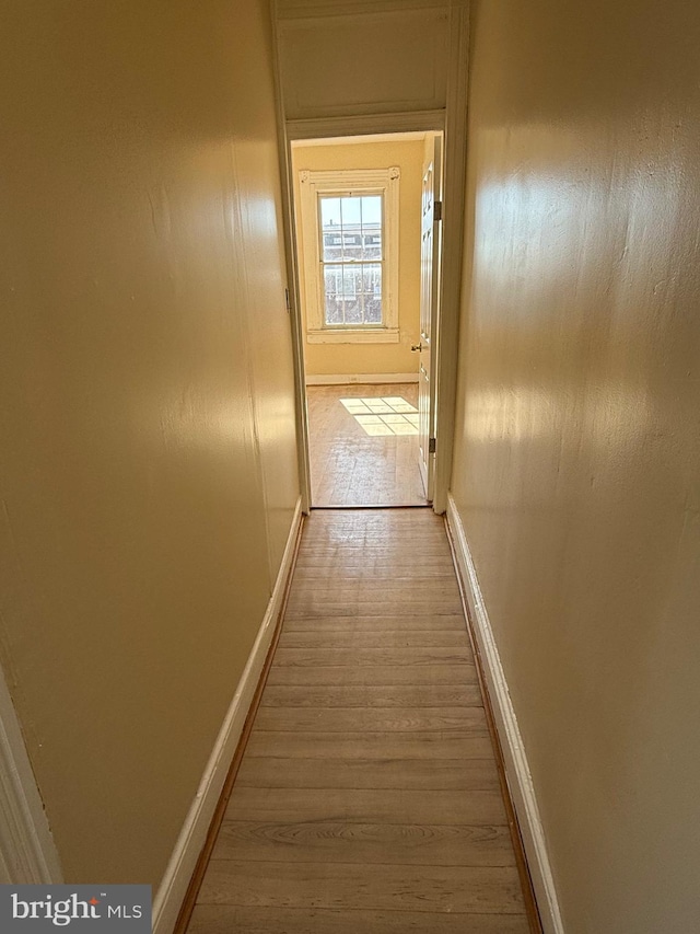 hallway featuring wood finished floors and baseboards