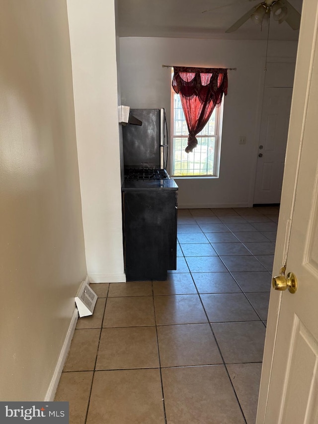 interior space with light tile patterned floors, visible vents, ceiling fan, and baseboards