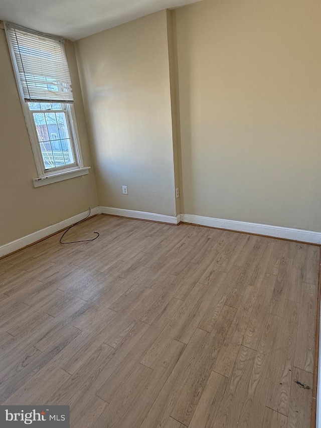 spare room with baseboards and light wood finished floors