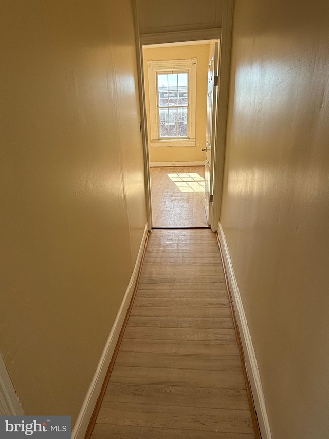 hall with light wood-style flooring and baseboards