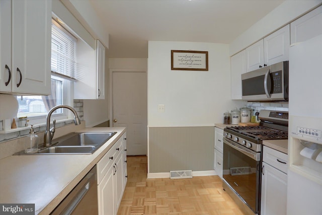 kitchen with visible vents, a sink, stainless steel appliances, light countertops, and white cabinets