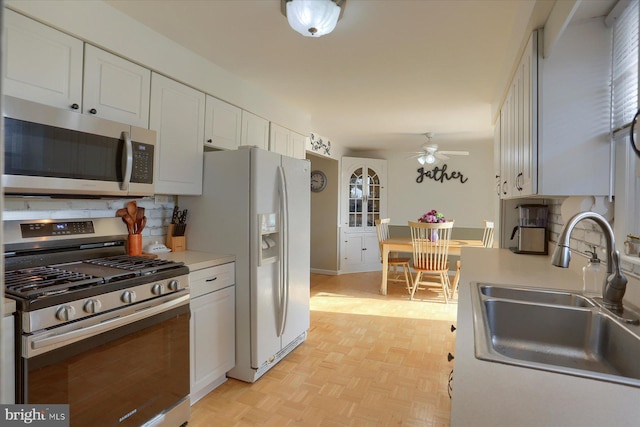 kitchen featuring a sink, stainless steel appliances, light countertops, and white cabinetry