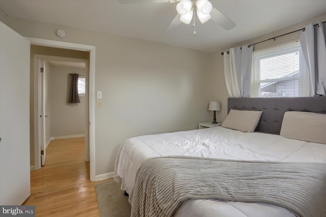 bedroom with light wood finished floors, multiple windows, baseboards, and ceiling fan