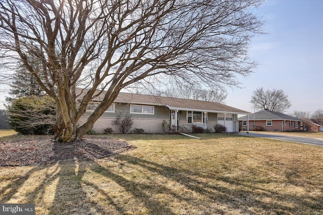 ranch-style house with a front lawn, brick siding, an attached garage, and driveway