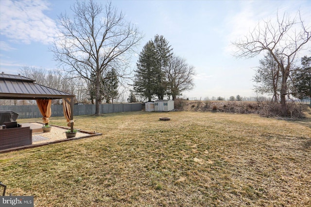 view of yard featuring a storage shed, a gazebo, an outbuilding, and fence