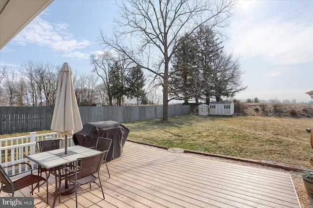 wooden deck featuring an outdoor structure, area for grilling, outdoor dining area, and a fenced backyard