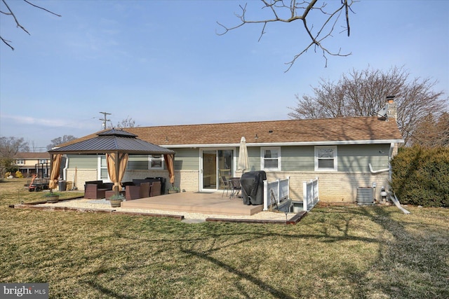 rear view of house with brick siding, central AC, a gazebo, a chimney, and a yard