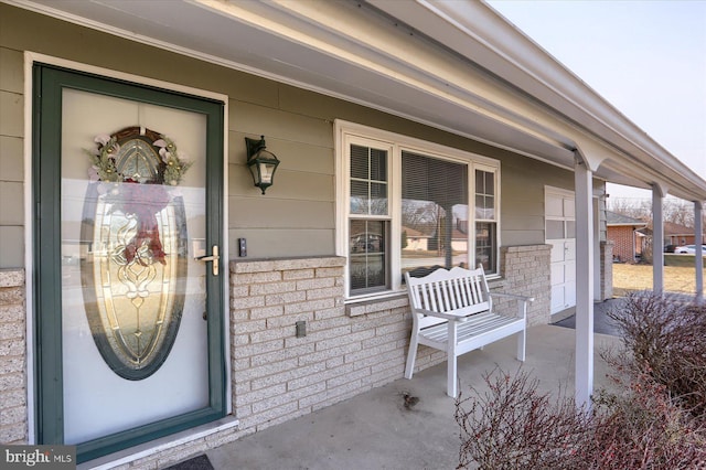 property entrance with brick siding and a porch