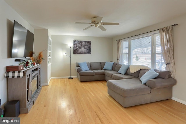 living room featuring ceiling fan, baseboards, and light wood-style flooring