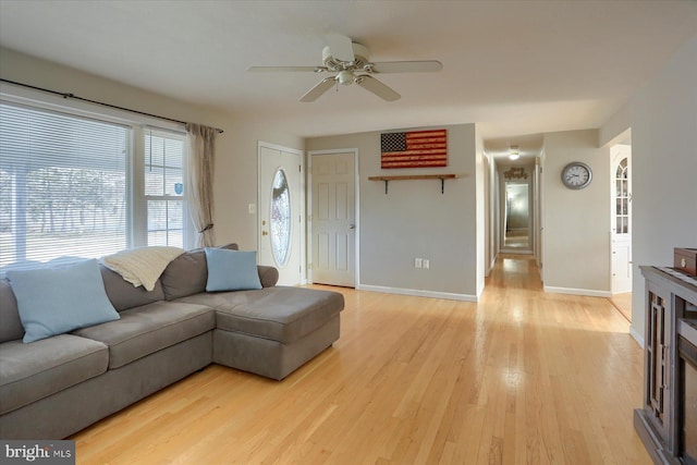 living room with ceiling fan, baseboards, and light wood-style flooring