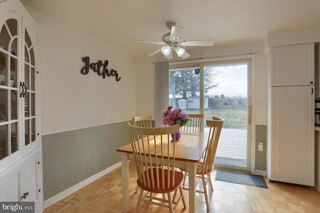 dining space with a wainscoted wall and a ceiling fan