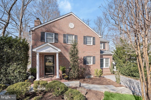 view of front of home featuring brick siding and a chimney