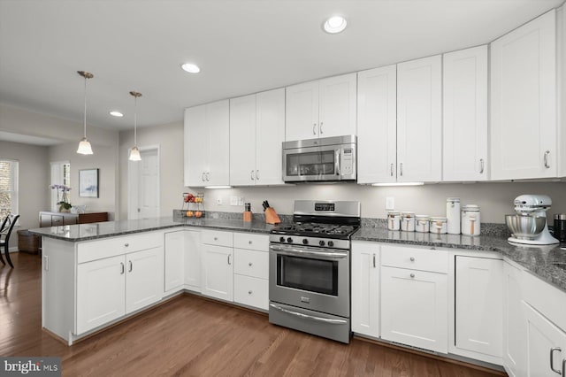 kitchen with a peninsula, recessed lighting, dark wood-type flooring, and stainless steel appliances