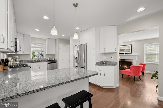 kitchen with a wealth of natural light, a sink, stainless steel appliances, and wood finished floors