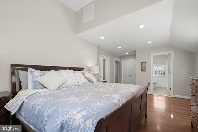 bedroom with visible vents, vaulted ceiling, recessed lighting, ensuite bathroom, and wood finished floors