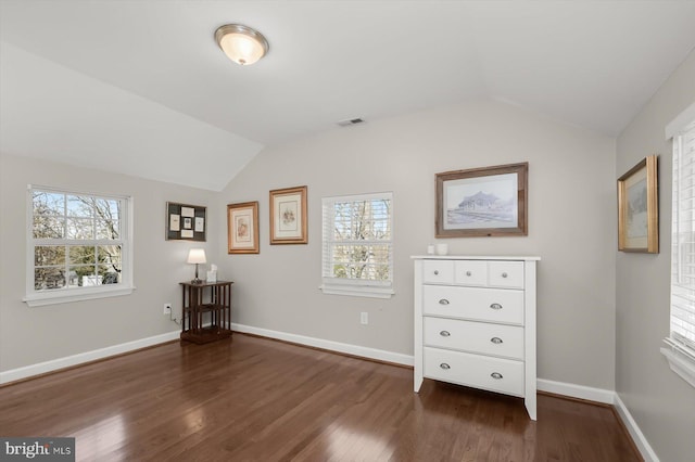 unfurnished bedroom featuring dark wood finished floors, lofted ceiling, and multiple windows