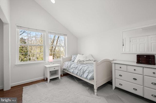 bedroom with vaulted ceiling, baseboards, and light wood finished floors