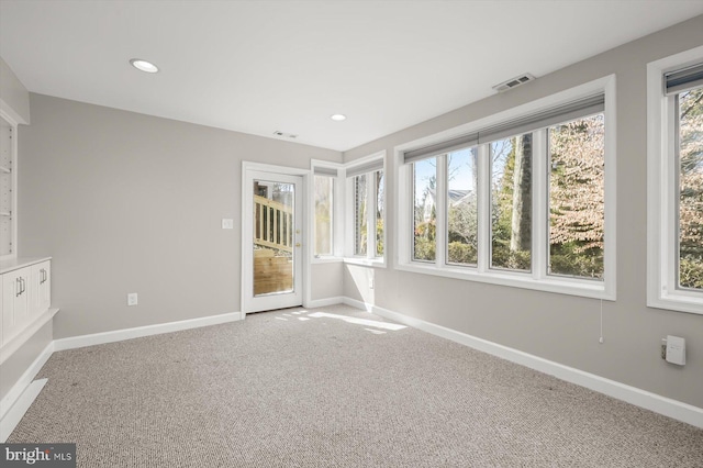 spare room with a wealth of natural light, baseboards, visible vents, and carpet floors