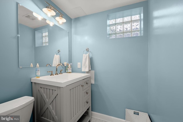 half bathroom featuring visible vents, toilet, vanity, and baseboards