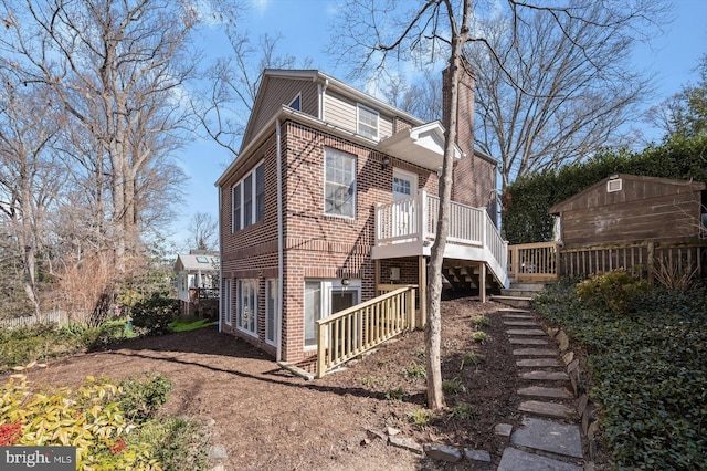 exterior space with brick siding, stairway, a chimney, a deck, and an outdoor structure