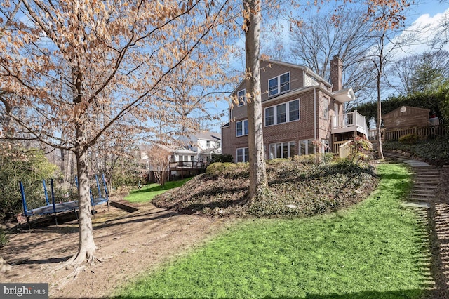 view of property exterior featuring brick siding, a wooden deck, a chimney, and stairs