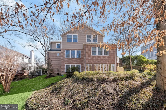 rear view of house with a lawn, brick siding, and fence