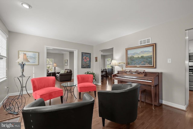 living area featuring wood finished floors, a healthy amount of sunlight, visible vents, and baseboards