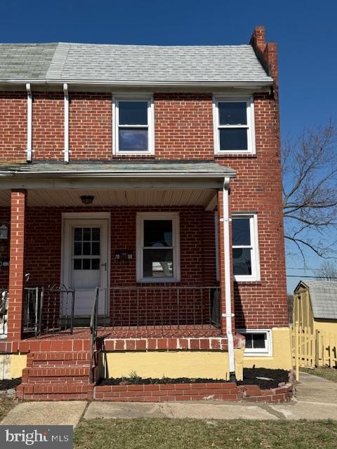 multi unit property featuring brick siding, covered porch, and a shingled roof