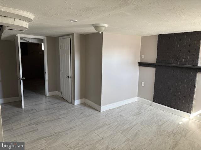 empty room featuring a textured ceiling and baseboards