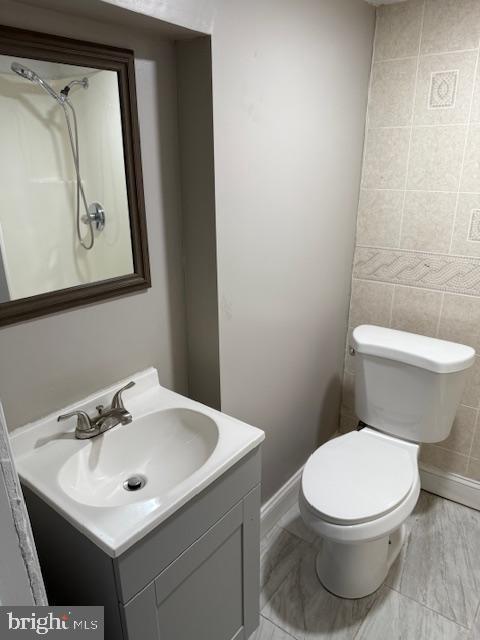 bathroom featuring toilet, vanity, and tile walls