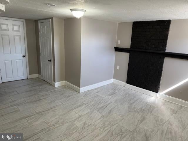 empty room featuring a fireplace, baseboards, and a textured ceiling