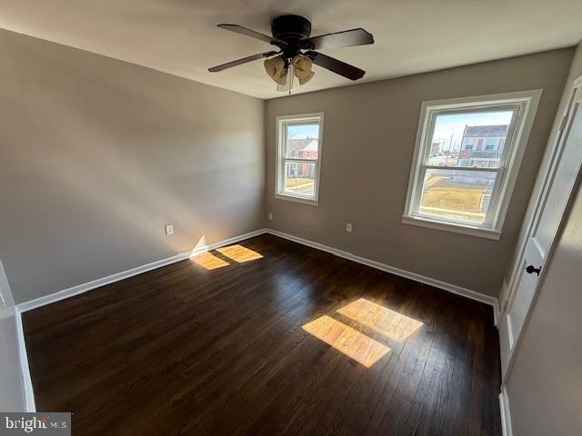 spare room with dark wood finished floors, ceiling fan, and baseboards